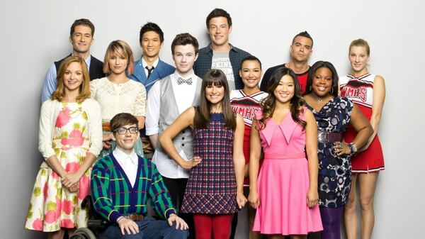 El elenco de Glee, con Corey Monteith en el centro, parado, y Salling a su izquierda, con una remera roja