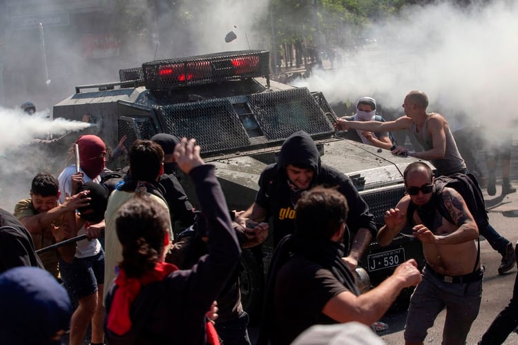 Manifestantes se enfrentan a un vehículo policial en Santiago (Foto: Claudio Reyes/ AFP)