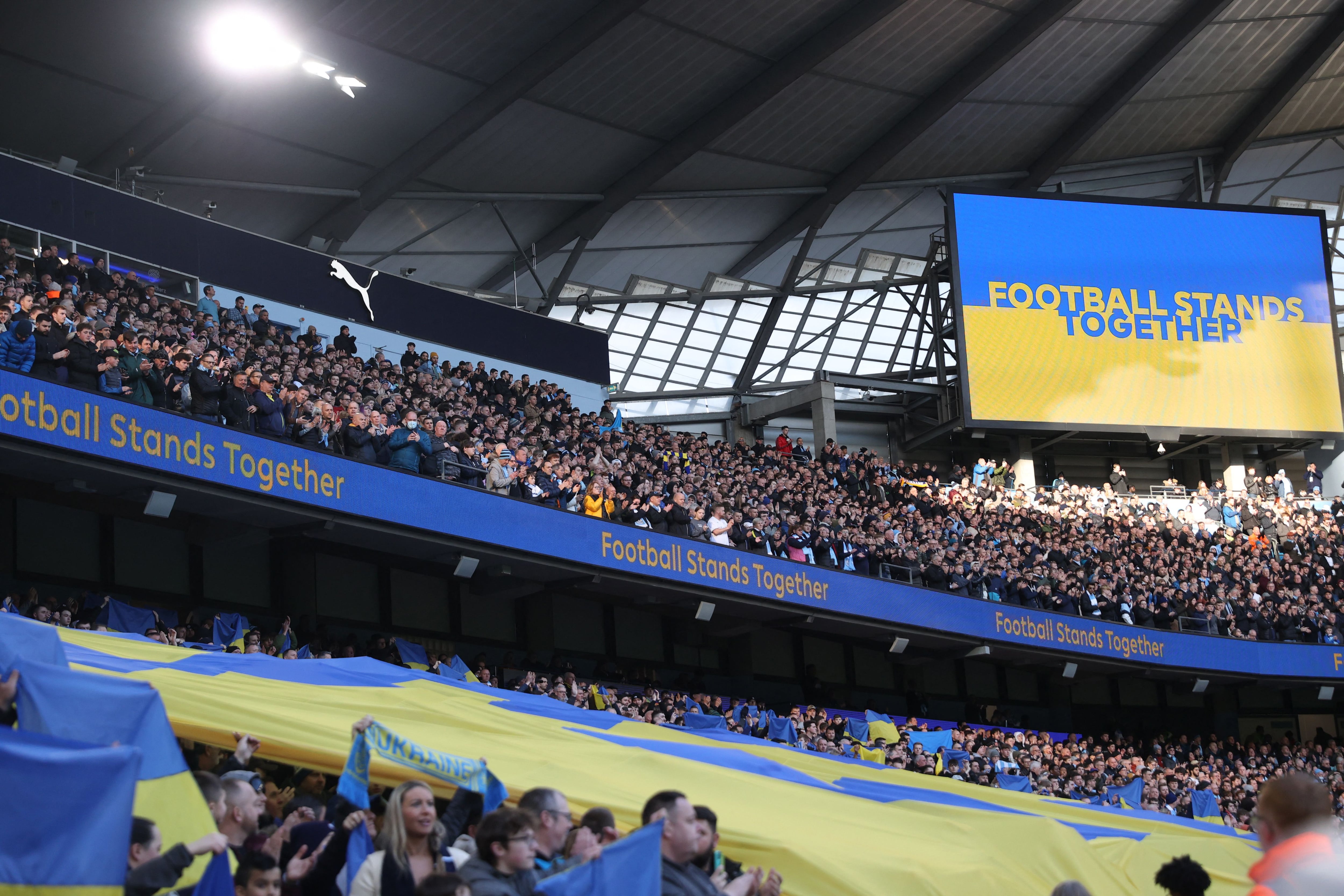 Las banderas en respaldo a Ucrania y el mensaje en la pantalla gigante durante el minuto de aplausos en repudio a la guerra en Manchester City-Manchester United (Reuters/Carl Recine)