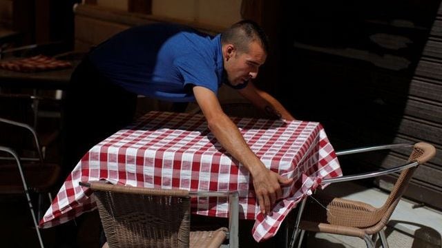 FILE PHOTO: A waiter arranges a tablecloth on the terrace of a restaurant in the center of Ronda, Andalusia, Spain, July 28, 2016. REUTERS/Jon Nazca