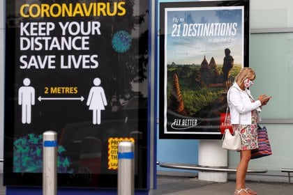 Una mujer aguarda su transporte, mientras utiliza una máscara protectora después de llegar al aeropuerto de Birmingham tras el brote de la enfermedad COVID-19, Gran Bretaña (Reuters)