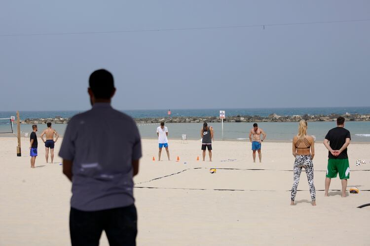 Israelíes esperan de pie en la playa mientras las sirenas marcan dos minutos de silencio en recuerdo de las seis millones de víctimas judías del Holocausto, en Tel Aviv, el 2 de mayo de 2019 (AP)