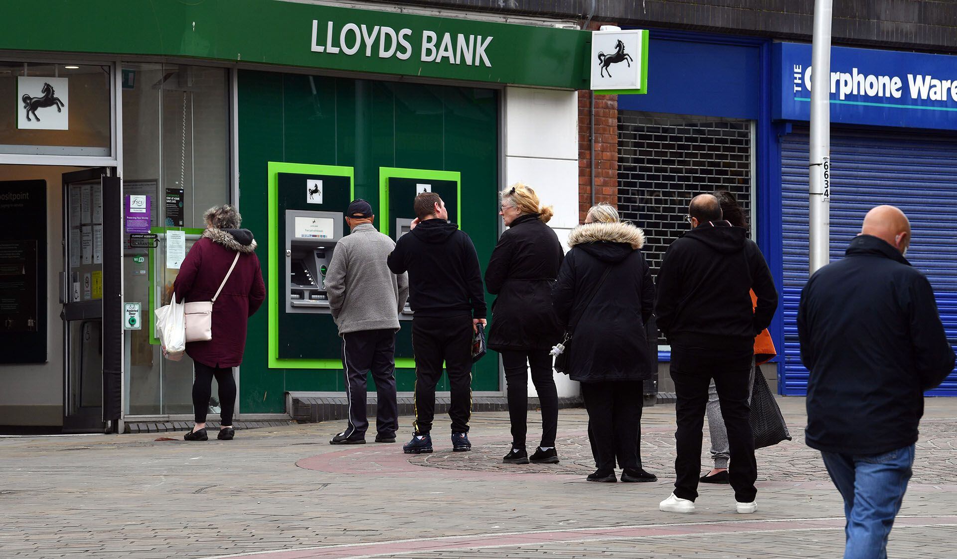 Una fila manteniendo la distancia social para obtener dinero en un cajero automático de Barrow-in-Furness, al noroeste de Inglaterra.