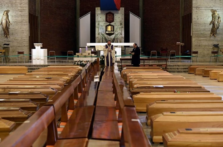 Un sacerdote bendice los ataúdes almacenados en una iglesia debido al alto número de muertes, antes de que se los lleven los camiones del ejército, mientras Italia lucha por contener la propagación del coronavirus (REUTERS)