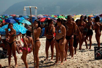 Bañistas hacen fila para refrescarse sin mantener la distancia social hoy, en la playa de Ipanema (EFE)