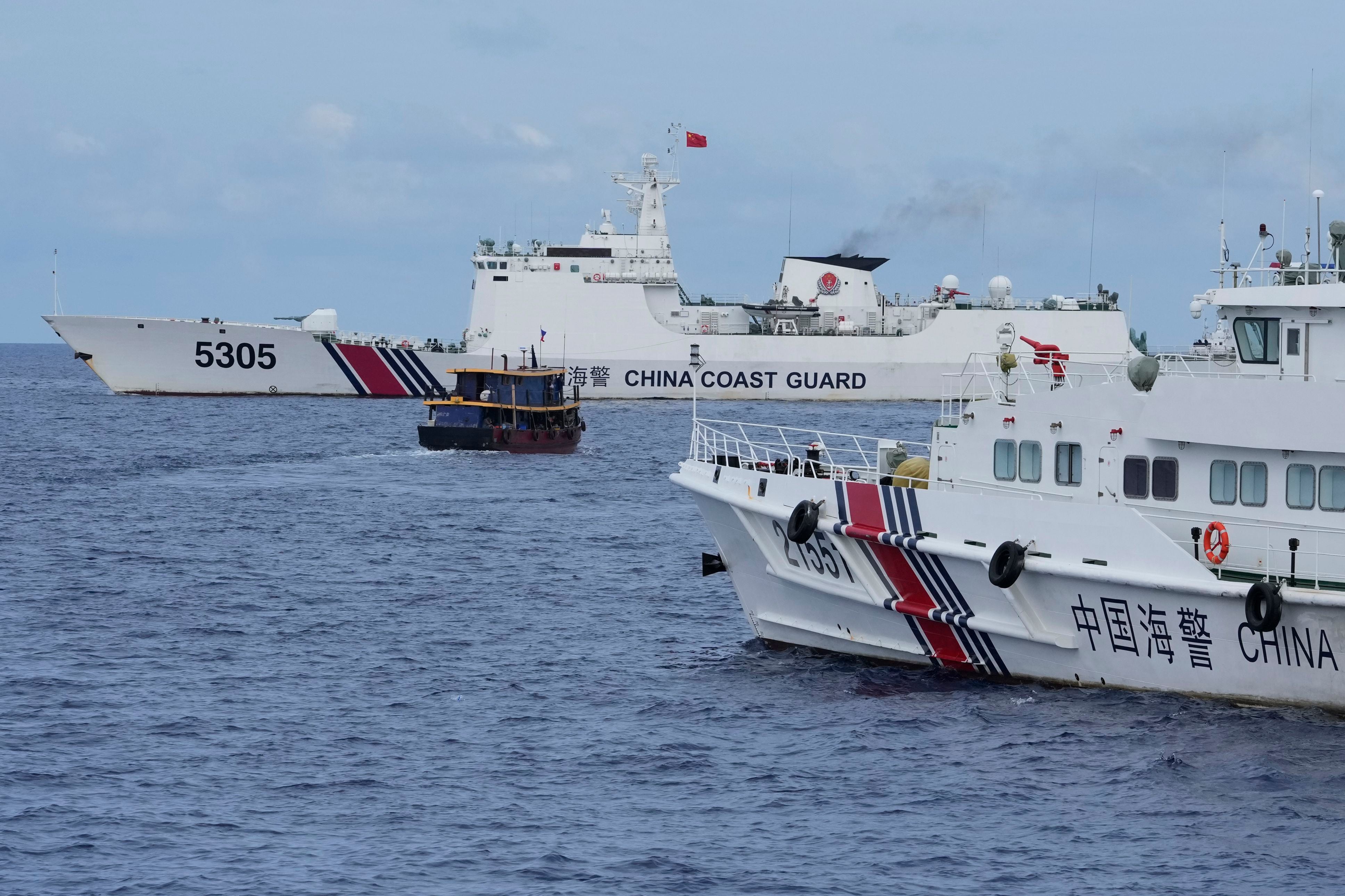 Un barco de suministros filipino (centro), maniobra alrededor de buques de la Guardia Costera de China   (AP Foto/Aaron Favila)