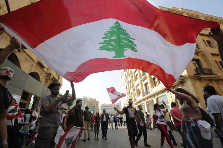 Protesters wave the national flag in downtown beirut as hundreds continued to gather on October 19, 2019 for a third day of protests against tax increases and alleged official corruption after the security forces made dozens of arrests. - Thousands of protesters outraged by corruption and proposed tax hikes burned tyres and blocked major highways in Lebanon on Friday, prompting the premier to give his government partners three days to support a reform drive. (Photo by ANWAR AMRO / AFP)