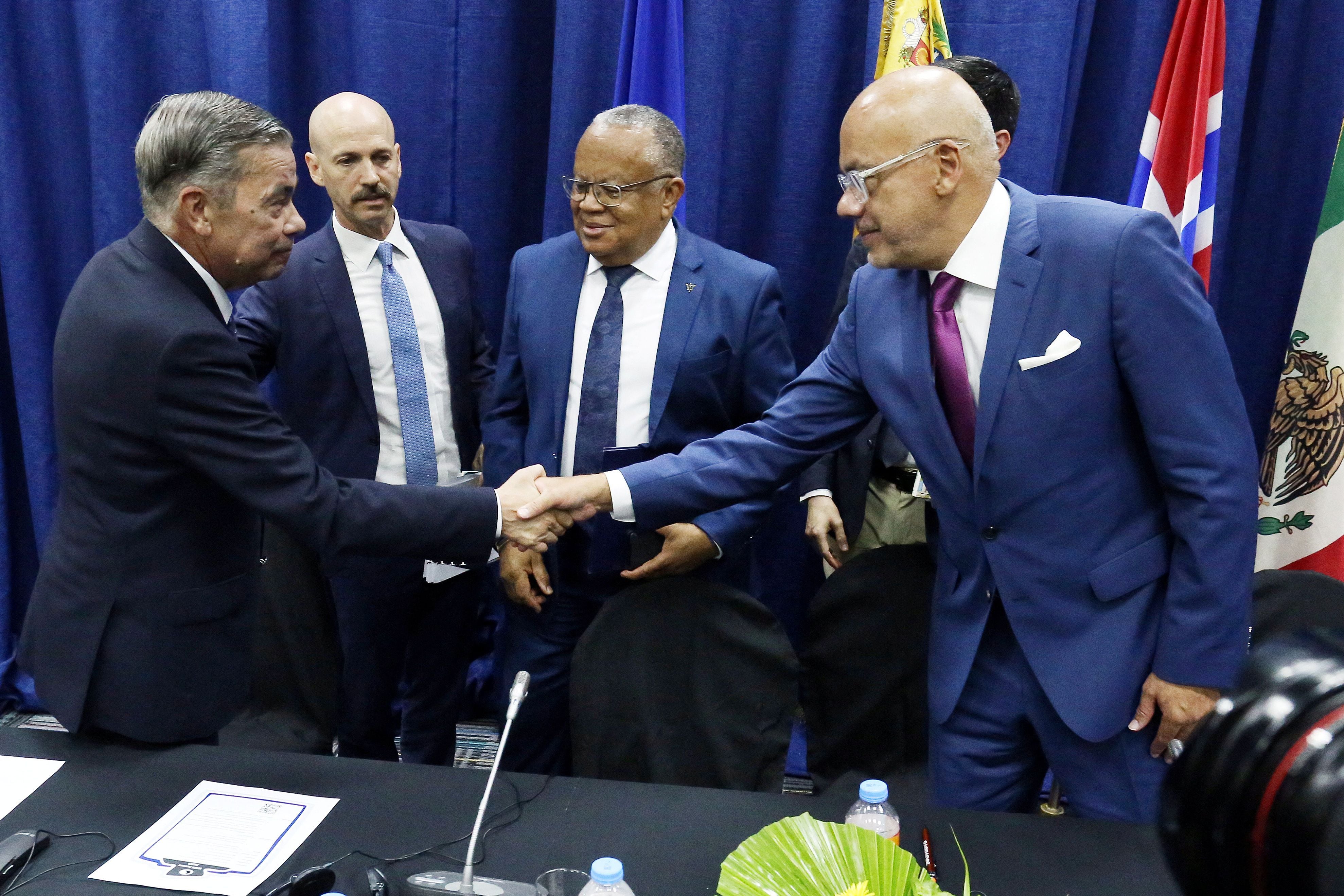 Gerardo Blyde le da la mano a Jorge Rodriguez tras la firma de los acuerdos entre la oposición y el régimen de Venezuela en Barbados (REUTERS/Nigel R. Browne/Nu-Image Digital Media)