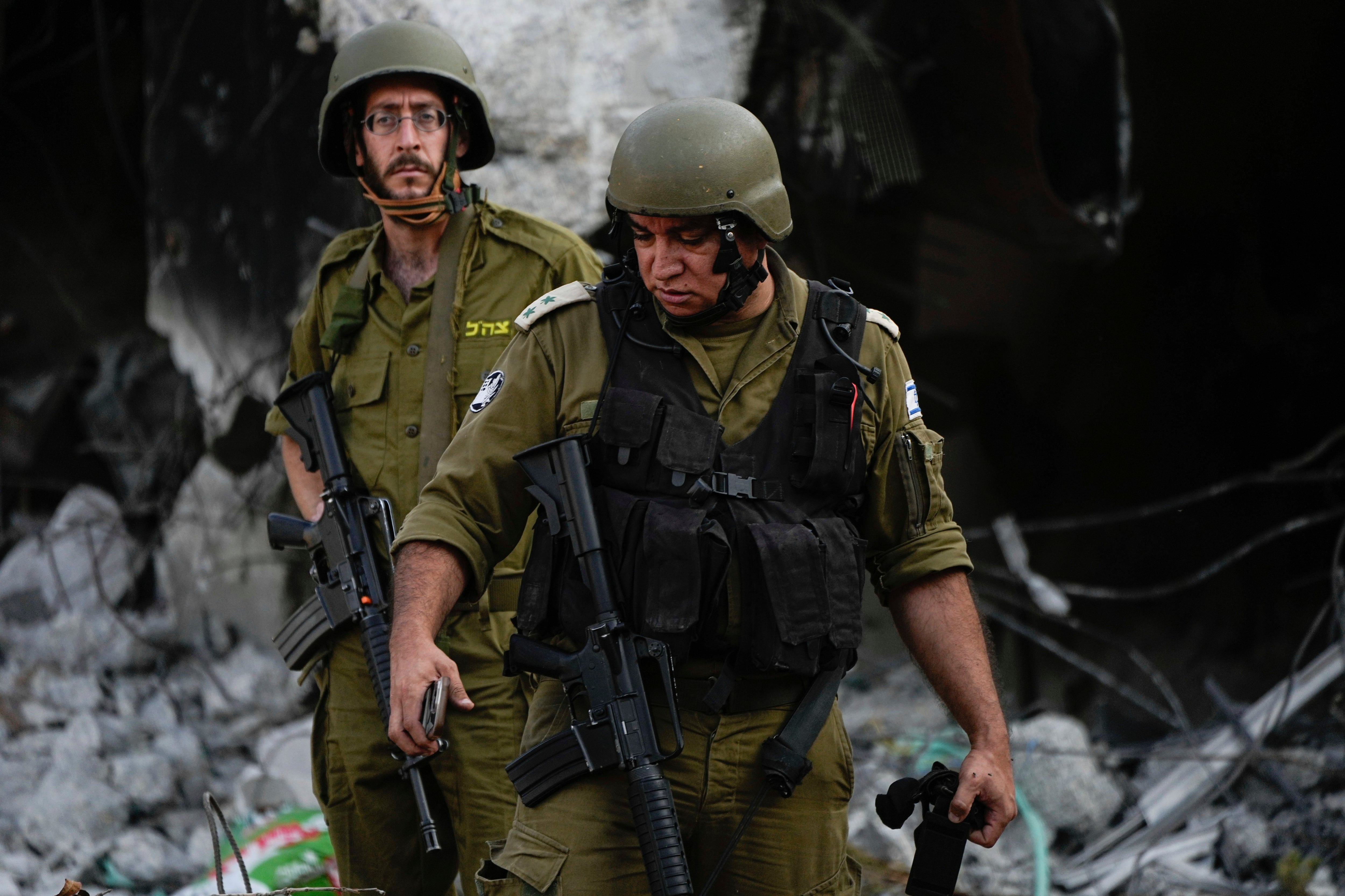 Soldados israelíes pasan junto a casas destruidas por milicianos de Hamas en el kibbutz Be'eri, Israel, el sábado 14 de octubre de 2023. La población fue tomada por milicianos de Hamas llegados de la vecina Franja de Gaza el 7 de octubre, cuando mataron y capturaron a muchos israelíes. (AP Foto/Ariel Schalit)