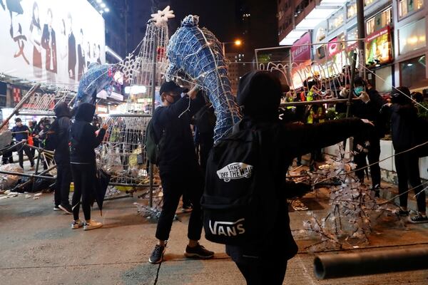 Manifestantes contra el gobierno desarman las decoraciones colocadas en las calles de Hong Kong para celebrar el año nuevo