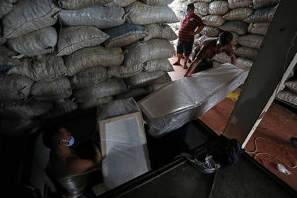 Los trabajadores llevan ataúdes, que llegaron del estado de Santa Catarina al Puerto de Manaus y fueron comprados por las funerarias, en medio del brote de la enfermedad coronavirus (COVID-19), en Manaos, 