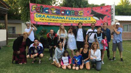 Adriana, de blanco y en el medio de la foto, en familia. Juntos celebraron los siete años que le costó recibirse de médica, a sus 58 años. “Felicitaciones por tu esfuerzo y dedicación, te amamos”, dice el cartel