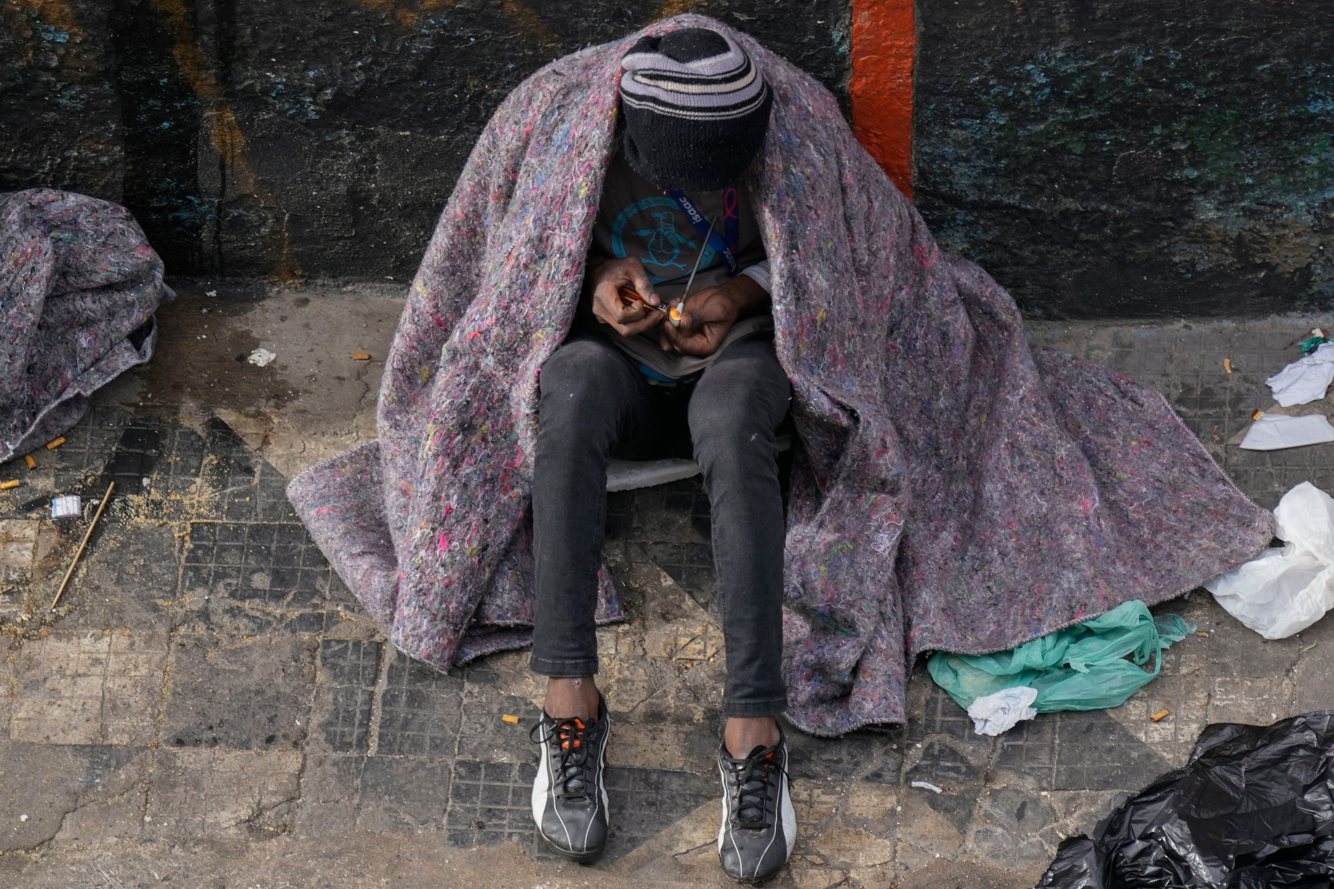 Un consumidor de drogas sin hogar fuma cocaína en el distrito comercial de Santa Efigenia, un importante centro comercial de productos y accesorios de electrónica en el centro de Sao Paulo, Brasil, el jueves 18 de mayo de 2023.  (AP Foto/Andre Penner)