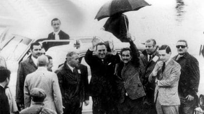 Perón llega a Morón, a su lado Juan Ignacio Rucci sostiene el paraguas 