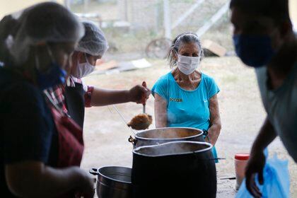 Una mujer espera a recibir un plato de comida para ella y su familia en un comedor social durante la pandemia coronavirus en Luque, Paraguay, el lunes 11 de mayo de 2020. (AP Foto/Jorge Sáenz)