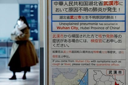 Una mujer con una mascarilla pasa cerca de un aviso de cuarentena puesto sobre la ciudad china de Wuhan por un nuevo virus, durante enero de 2020 (REUTERS/Kim Kyung-Hoon)