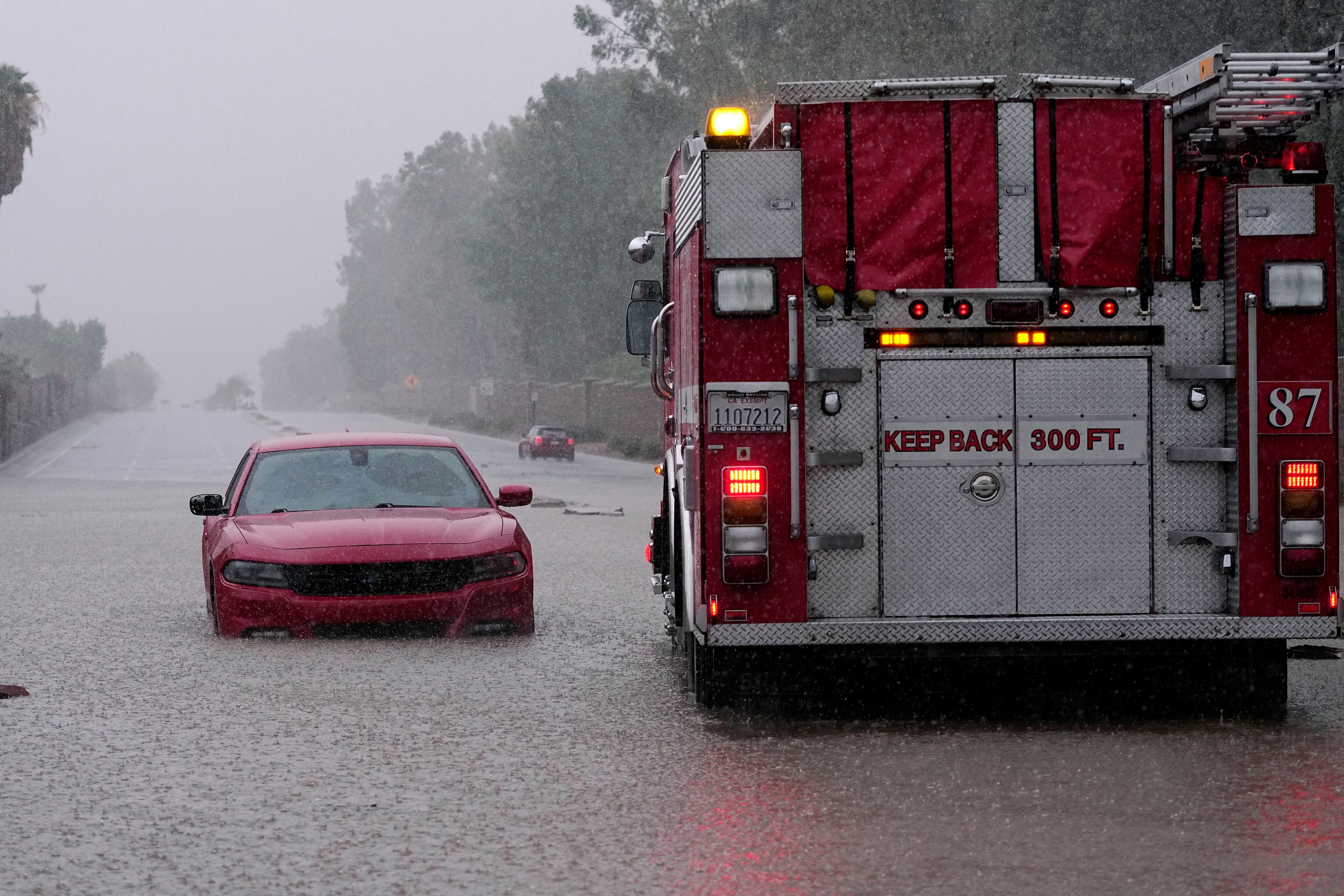 Un camión de bomberos se echa en reversa después de que un automovilista quedó varado en una inundación por las lluvias torrenciales que trajo la tormenta tropical Hilary en Palm Desert, California. 