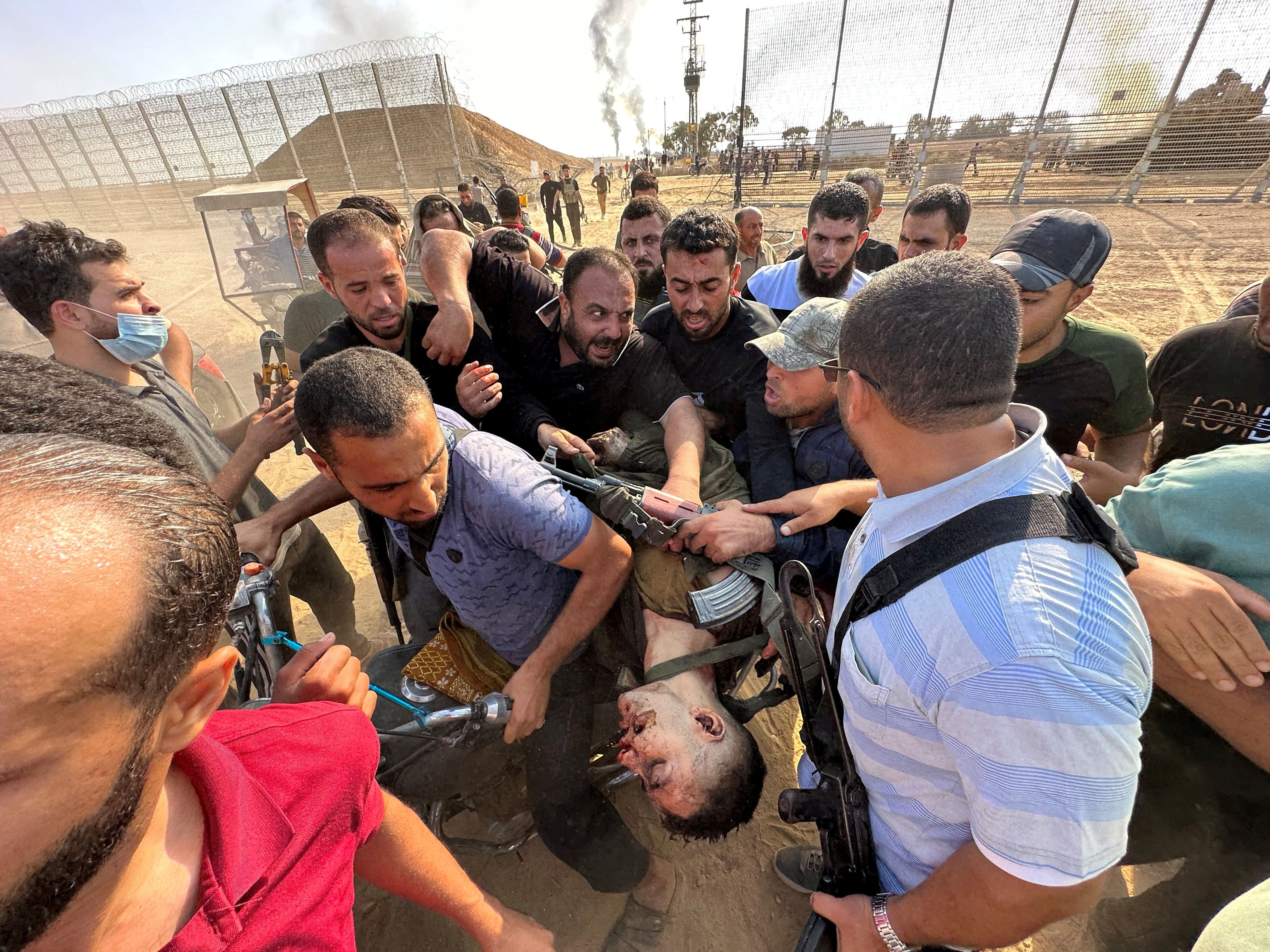 Palestinos portan el cadáver de quien dicen es un israelí asesinado por terroristas de Hamás que se infiltraron en zonas del sur de Israel este 7 de octubre (Reuters)