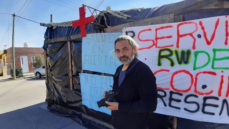 Anibal Aguaisol sostiene su cámara frente al “Centro de Atención Precaria” del Hospital Santa Teresita de Rawson en el que trabaja