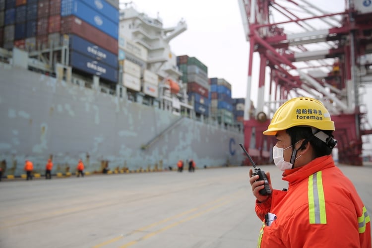 Un trabajador con barbijo cerca de un buque de carga en una terminal de contenedores del puerto de Qingdao en la provincia de Shandong, China, en una foto del 4 de febrero de 2020. (cnsphoto a través de REUTERS)