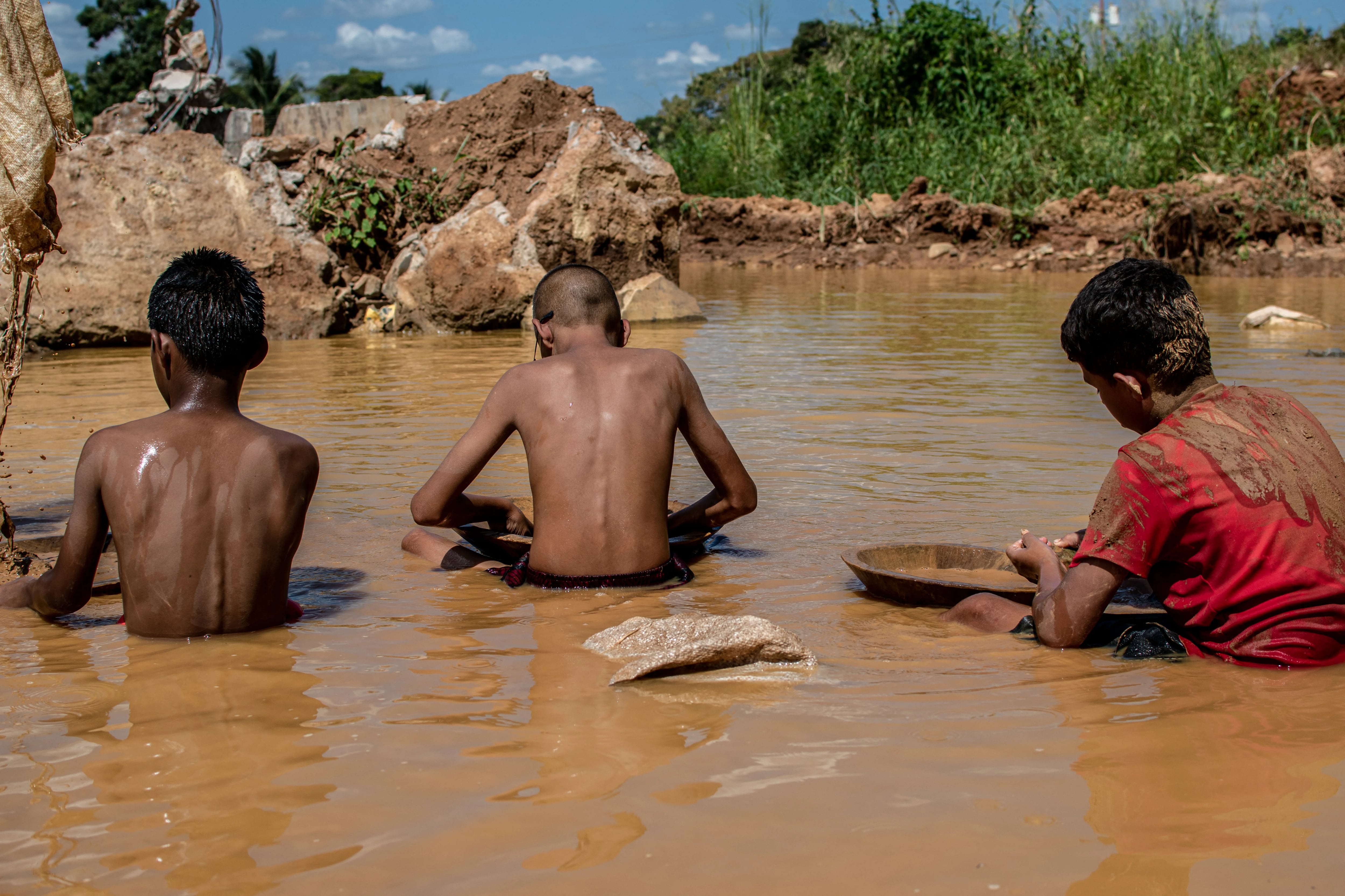 Venezuelan mining children work in a puddle of water and mud while searching for gold in an open pit mine in El Peru community, El Callao, Bolivar State, Venezuela, on September 2, 2023. In the town of El Callao, extracting gold from soil starts off as a kid's game, but soon becomes a full-time job that human rights activists says amounts to child exploitation. (Photo by Yris PAUL / AFP)