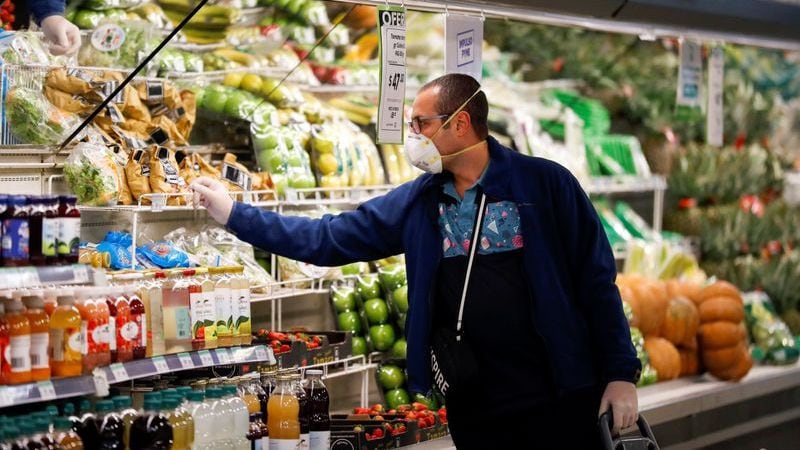 Un hombre con barbijo compra en un supermercado mientras los habitantes comienzan a acopiar alimentos tras el brote de coronavirus, en Buenos Aires. REUTERS/Agustin Marcarian