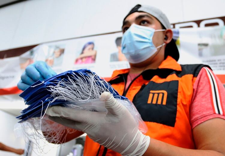 Un trabajador de Mero de la Ciudad de México reparte cubrebocas a los usuarios para evitar la propagación del Covid-19. (Foto: EFE/ JOSE PAZOS) 