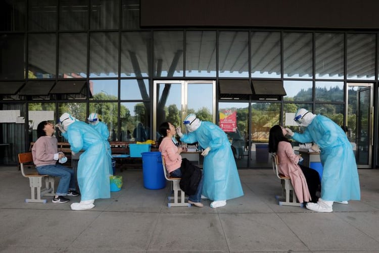 Trabajadores médicos de un hospital recolectan muestras de profesores de secundaria para pruebas de ácido nucleico en una escuela de Wuhan (China Daily via REUTERS)