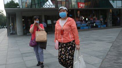 A woman wearing a face mask walks past an Adidas store at the Sanlitun shopping area, following the outbreak of the coronavirus disease (COVID-19), in Beijing, China July 1, 2020. REUTERS/Tingshu Wang