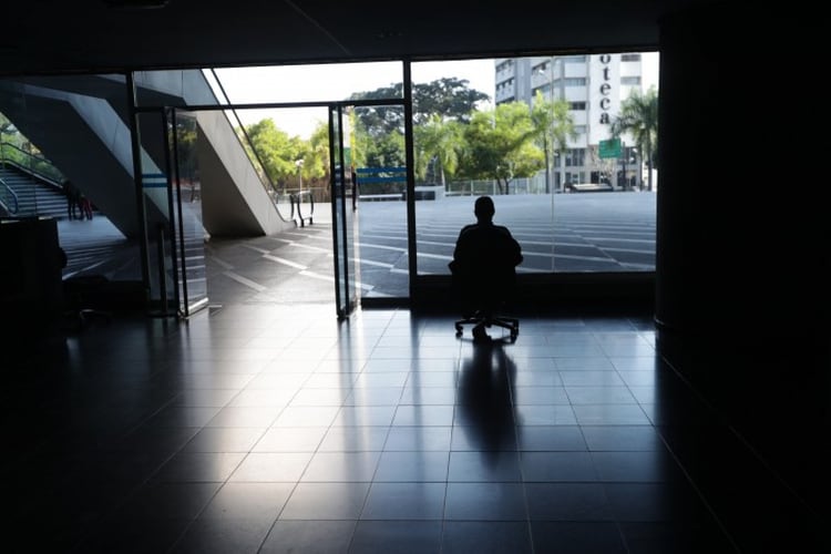 Un hombre mira por la ventana en una oficina sin luz en Caracas (EFE/ Rayner PeÃ±a)