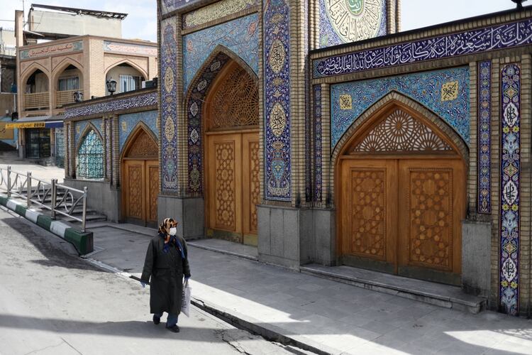 Una mujer con una máscara facial protectora y guantes pasa por delante del santuario de Imamzadeh Saleh, en medio del temor a la enfermedad coronavirus (COVID-19), en Teherán, Irán, el 2 de abril de 2020. WANA (Agencia de Noticias de Asia Occidental)/Ali Khara vía REUTERS 