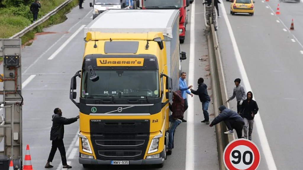 Inmigrantes intentan subir a un camión por la fuerza en Calais, rumbo a Reino Unido
