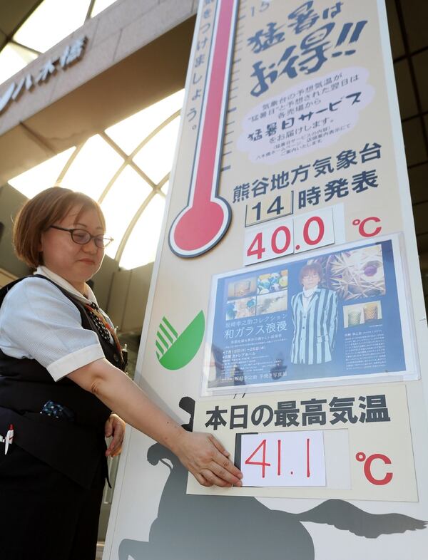 En Kumagaya, Japón, una mujer actualiza las inverosímiles temperaturas en un panel de un centro comercial, en julio de 2018. (Jiji Press/Japan Out/AFP)
