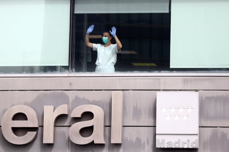 Un médico de cuidados intensivos del hospital La Paz, en Madrid saluda desde una ventana luego de atender pacientes en grave estado por el coronavirus. REUTERS/Sergio Perez