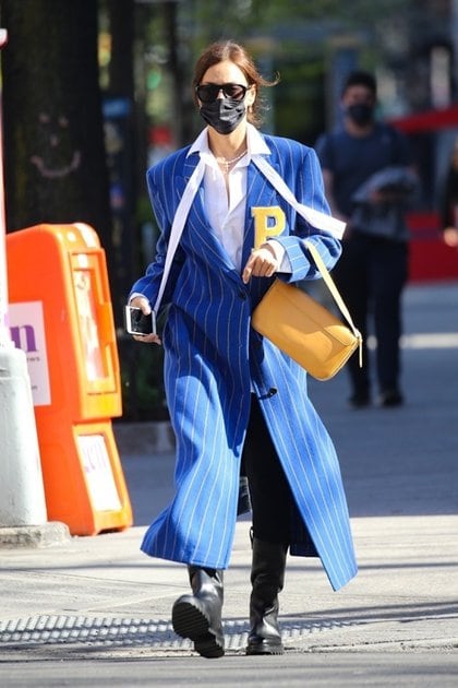 Irina Shayk paseó por Nueva York y no pasó desapercibida. La modelo optó por un look de leggings y botas negras, camisa blanca y tapado azul con rayas blancas, y una letra P de terciopelo amarillo, color que combinó con su cartera de cuero