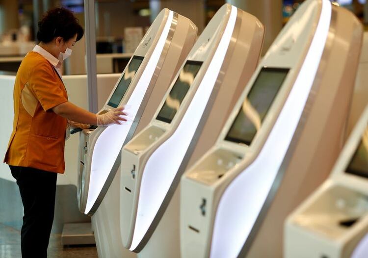 FOTO DE ARCHIVO. Un trabajador lleva una mascarilla de protección mientras limpia las máquinas de check-in en el aeropuerto de Singapur (REUTERS/Edgar Su)