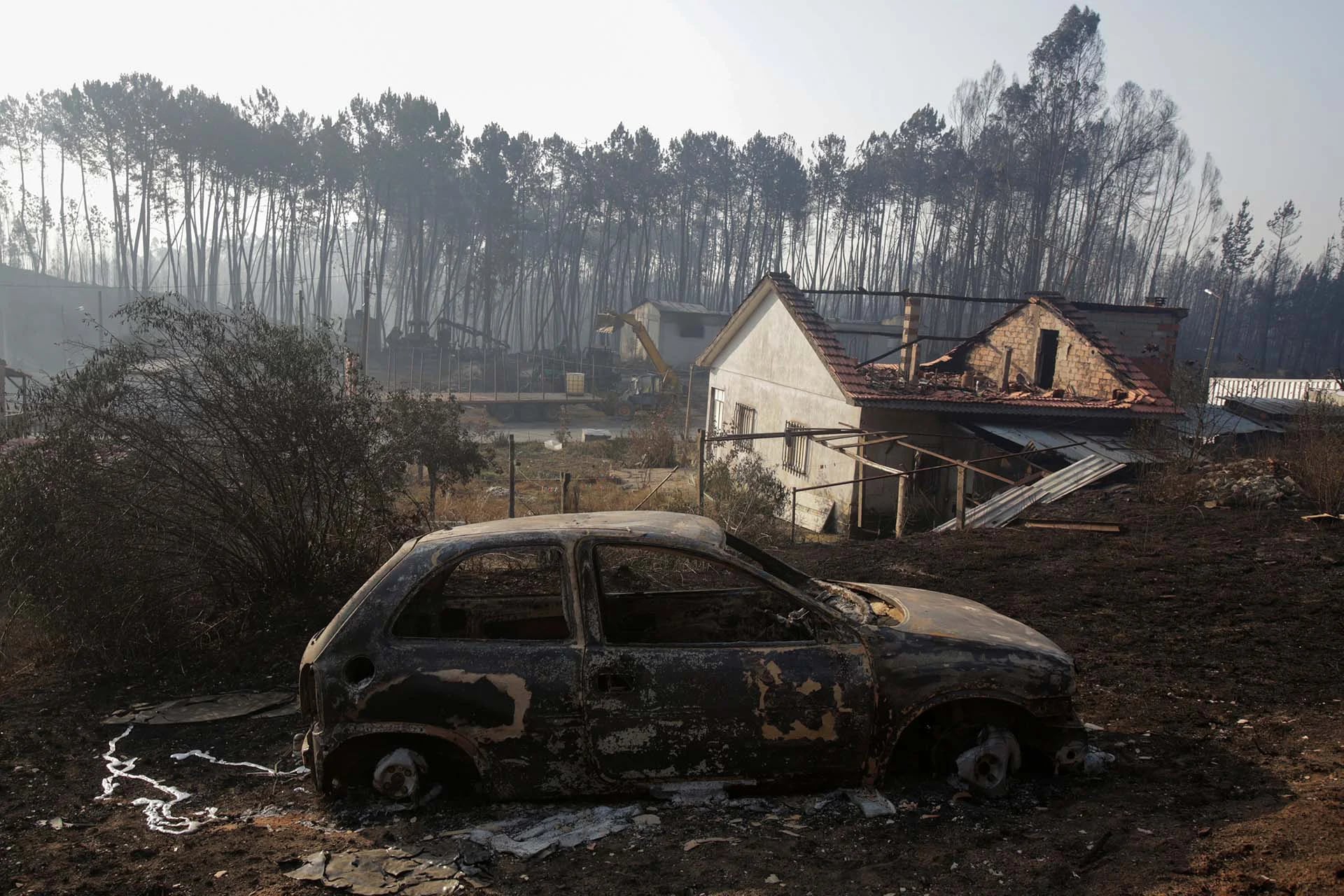Un automóvil carbonizado y una casa parcialmente destruida tras el incendio forestal en Castanheira de Pera, Portugal