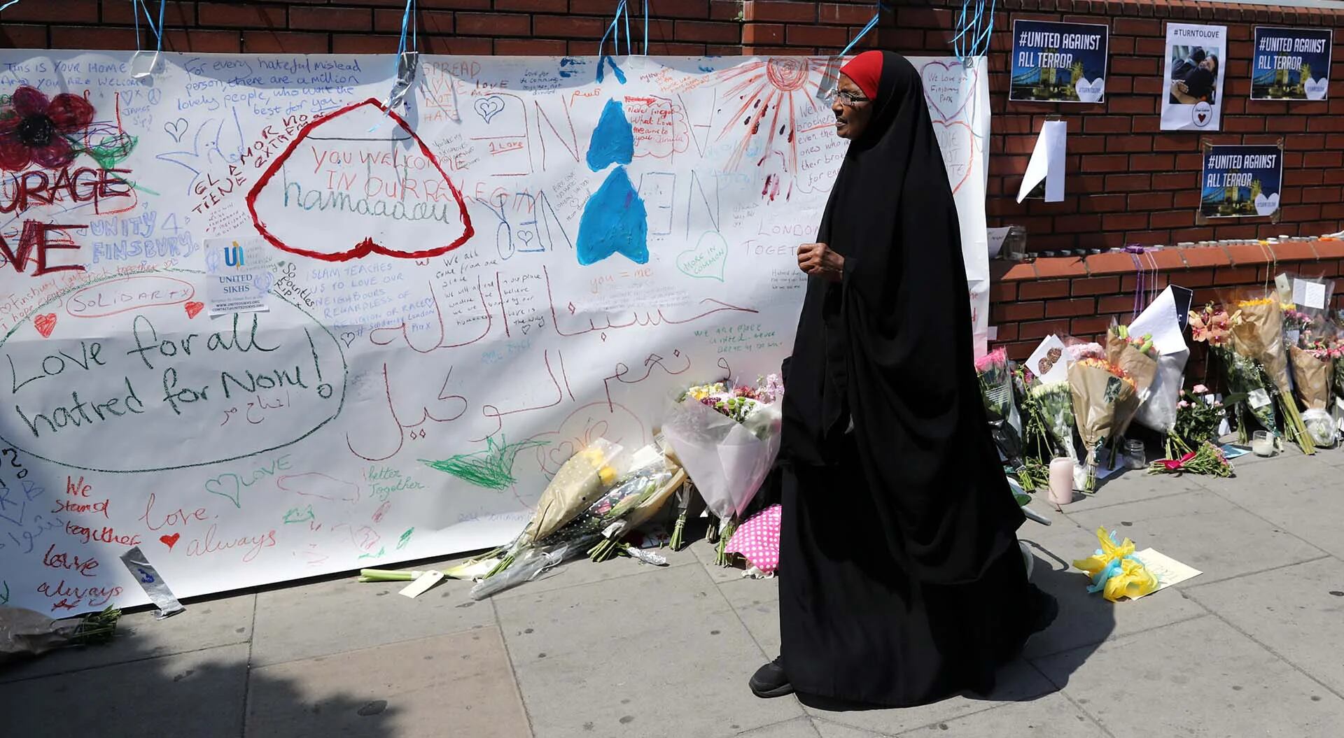Una mujer camina delante de los mensajes por el reciente atentado contra la Mezquita del Parque Finsbury en el norte de Londres, Reino Unido