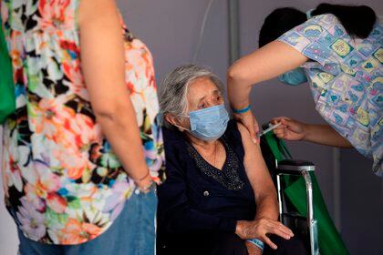 Una enfermera le administra una vacuna a una mujer en un centro de vacunación masivo localizado en la comuna de La Florida en Santiago (EFE/Alberto Valdés/Archivo)