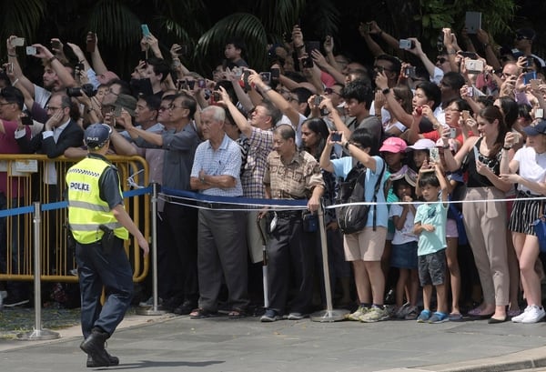 Ciudadanos de Singapur observan el paso del auto de Donald Trump  (AP Photo/Joseph Nair)