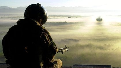 Un tripulante del Escuadrón 27 de la RAF maneja la ametralladora M60 montada en la parte trasera del portón trasero de su Chinook mientras transita por el campo afgano en la niebla de la mañana - 17 de abril de 2002 (Tony Leather/Royal Navy/Shutterstock)