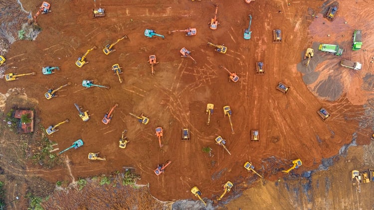 La toma aérea de más de 50 máquinas que trabajan sin descanso para acondicionar el suelo del sitio elegido para construir un hospital en Wuhan, China. (Photo by STR / AFP) / China OUT