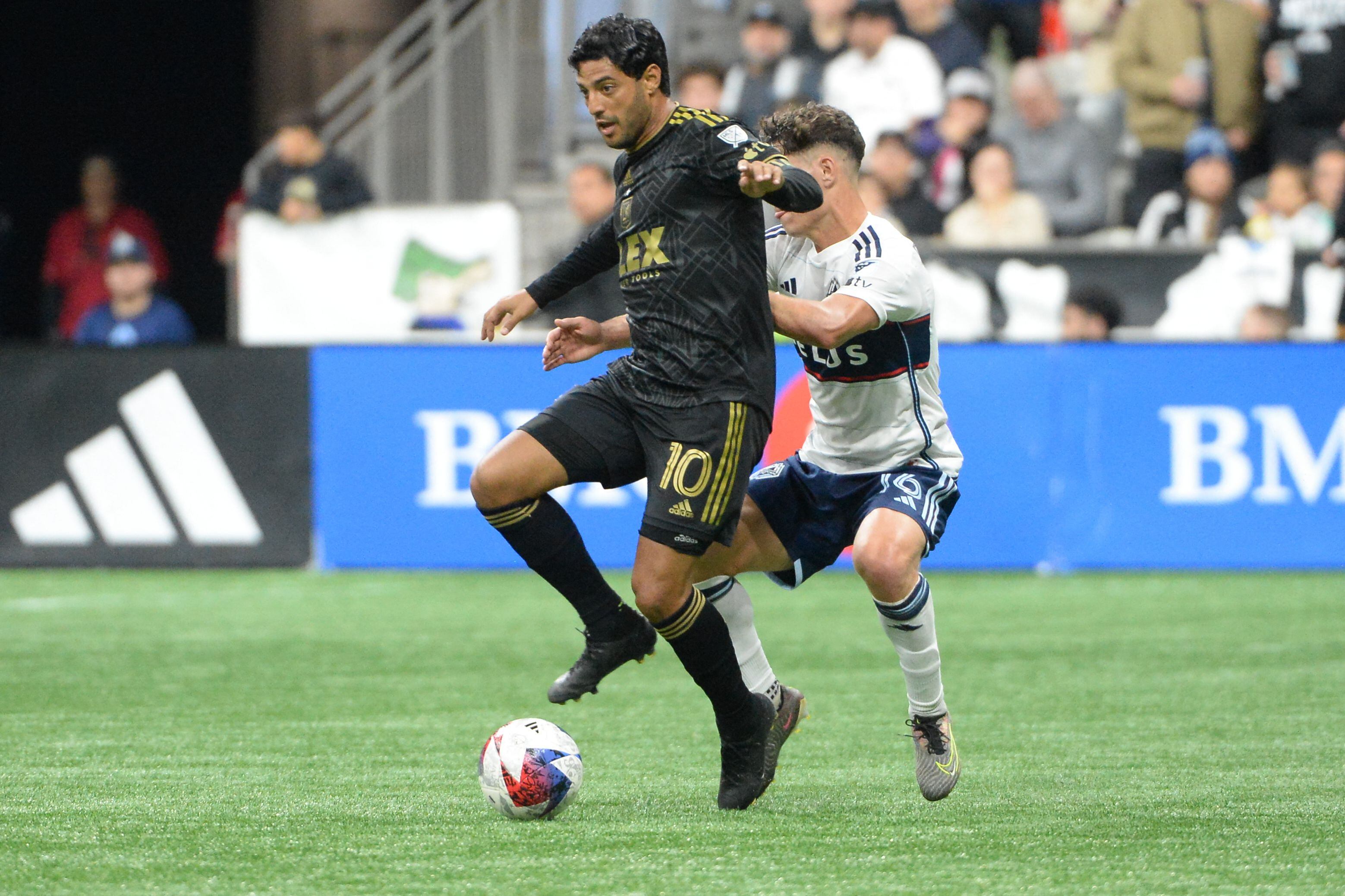 Oct 21, 2023; Vancouver, British Columbia, CAN;  Los Angeles FC forward Carlos Vela (10) controls the ball Vancouver Whitecaps FC midfielder Sebastian Berhalter (16) during the first half at BC Place. Mandatory Credit: Anne-Marie Sorvin-USA TODAY Sports
