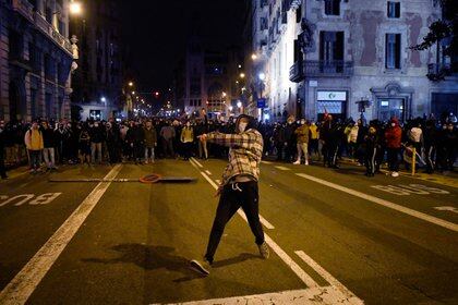 A protester throws an object to police following a demonstration against the imprisonment of Spanish rapper Pablo Hasel in Barcelona on February 21, 2021. - Looting broke out as police and demonstrators in Barcelona clashed for a fifth night yesterday with thousands hitting the streets across Spain in protest against the jailing of a controversial rapper. Angry demonstrations first erupted on February 16 after police detained Pablo Hasel, 32, and took him to jail to start serving a nine-month sentence in a highly contentious free speech case. (Photo by Pau BARRENA / AFP)