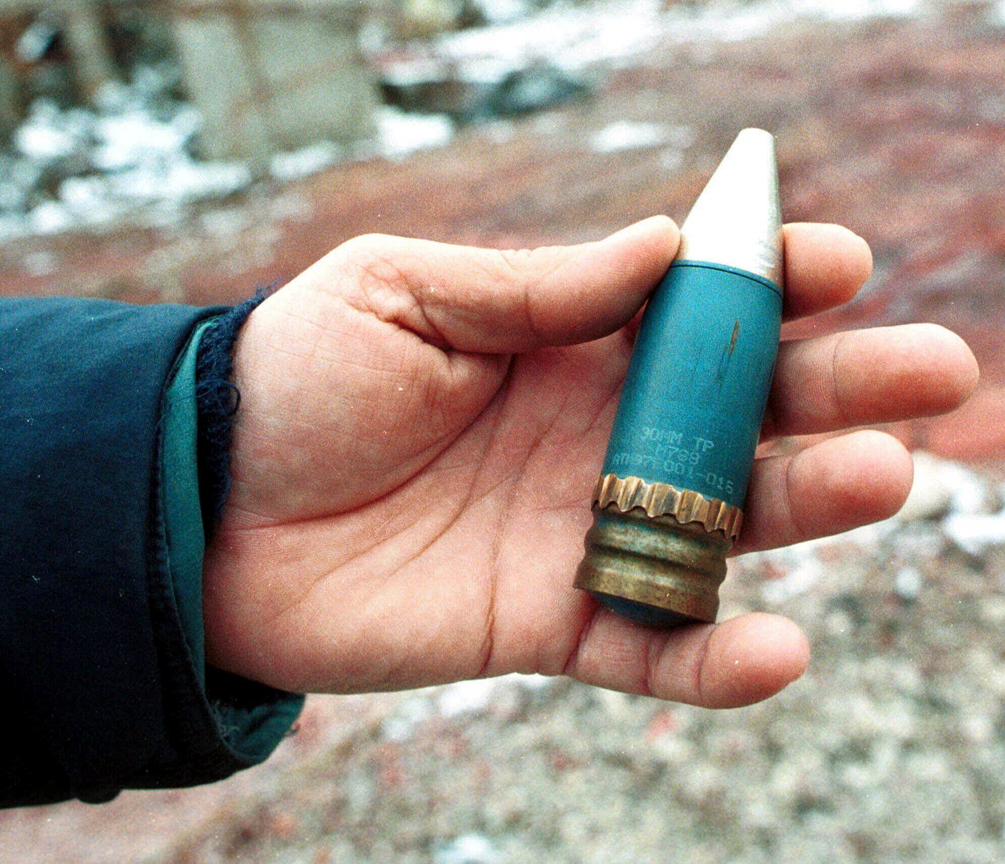 Un miembro de un equipo de especialistas en radiación sostiene un proyectil perforante de 30 mm que contiene uranio empobrecido, utilizado por la OTAN durante los ataques aéreos contra Bosnia en 1995. (AP Foto/Hidajet Delic, Archivo)