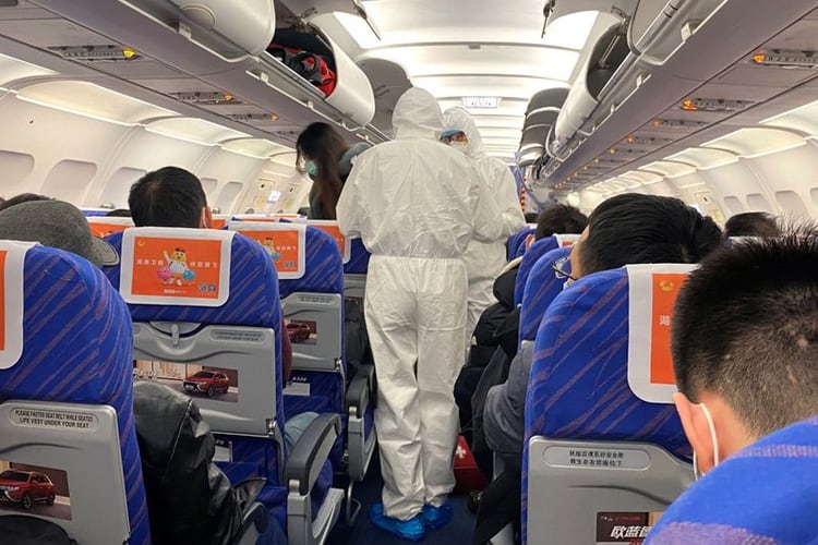 Trabajadores de salud con trajes protectores verifican la condición de un pasajero en un avión que acaba de aterrizar desde Changsha, una ciudad en una provincia vecina al centro del brote de coronavirus, en Shanghái, China. 25 de enero de 2020. REUTERS/David Stanway
