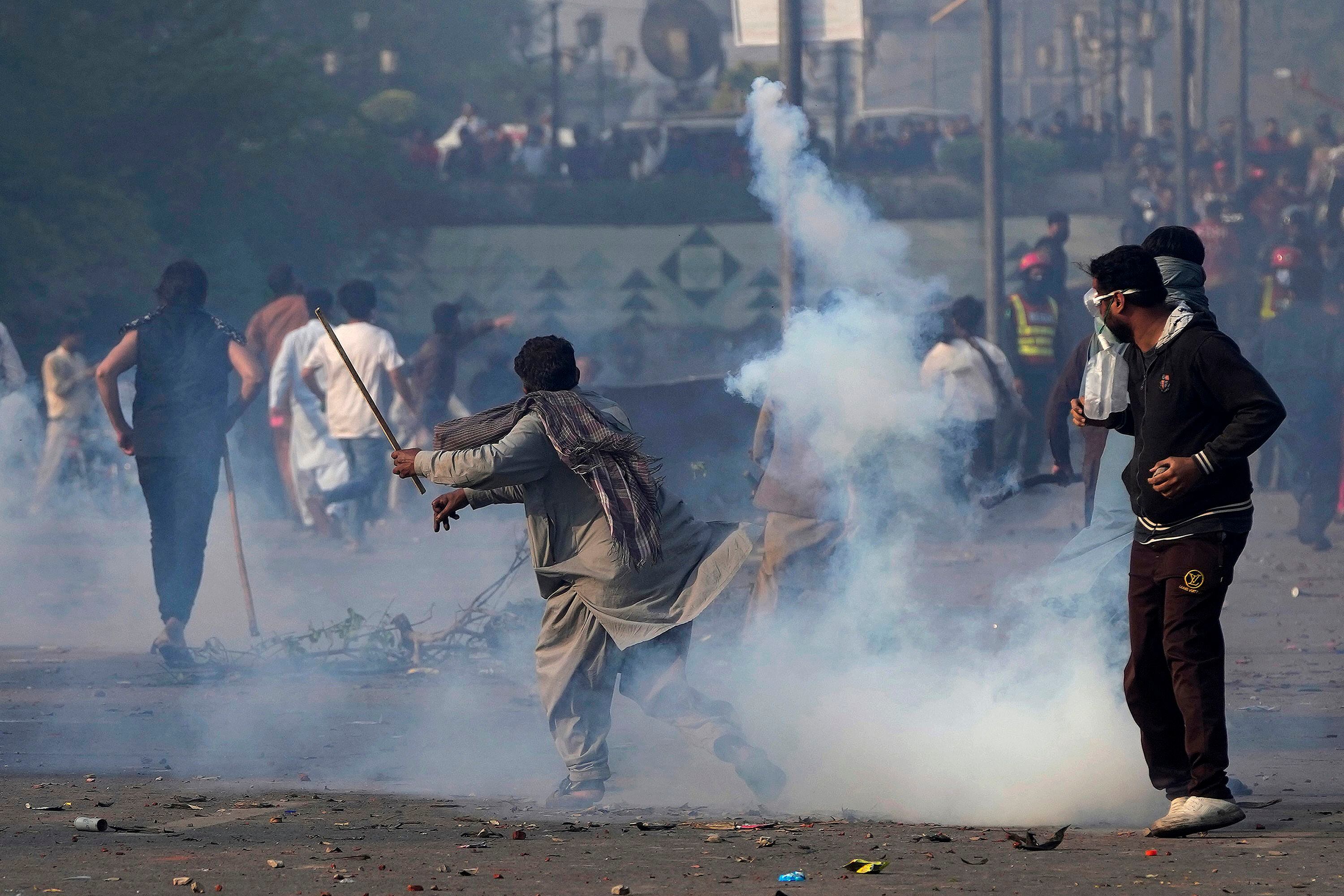 Un partidario del exprimer ministro de Pakistán Imran Khan lanza de vuelta una lata de gas lacrimógeno empleada por agentes de policía antimotines para dispersar a la multitud, durante enfrentamientos entre policía paquistaní y defensores de Khan en la ciudad natal del exmandatario, Lahore, el miércoles 15 de marzo de 2023. La policía intentó detener a Khan el día anterior por no comparecer ante una corte para responder de acusaciones de corrupción. (AP Foto/K.M. Chaudary)