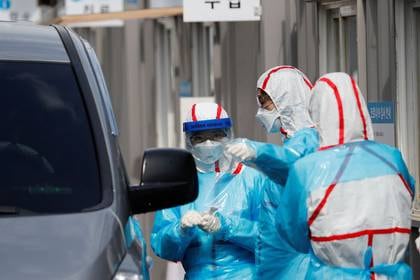  Personal médico con equipo de protección se prepara para tomar muestras de los visitantes en sus coches en un centro de pruebas del COVID-19 en el Centro Médico de la Universidad de Yeungnam, en Daegu, Corea del Sur