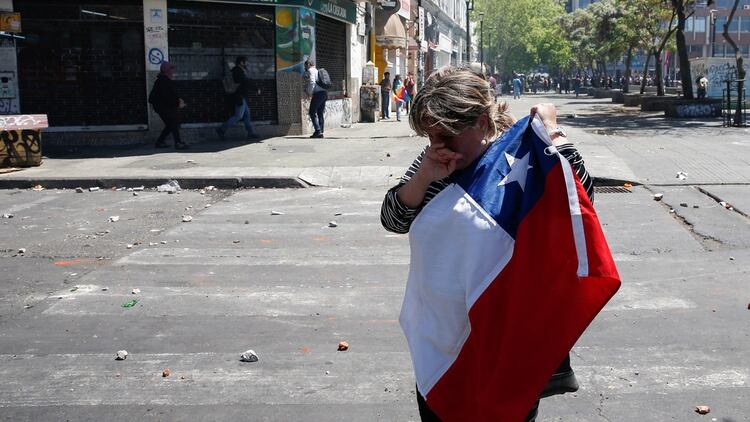 Una mujer llora con la bandera de Chile en mano