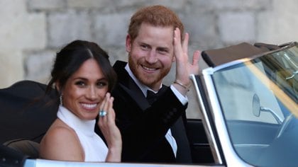 El príncipe Harry de Inglaterra, (D) y su esposa Meghan Markle (I), duques de Sussex, abandonan el castillo en Windsor el 19 de mayo de 2018 para festejar su enlace en una recepción nocturna en Frogmore House (AFP)  